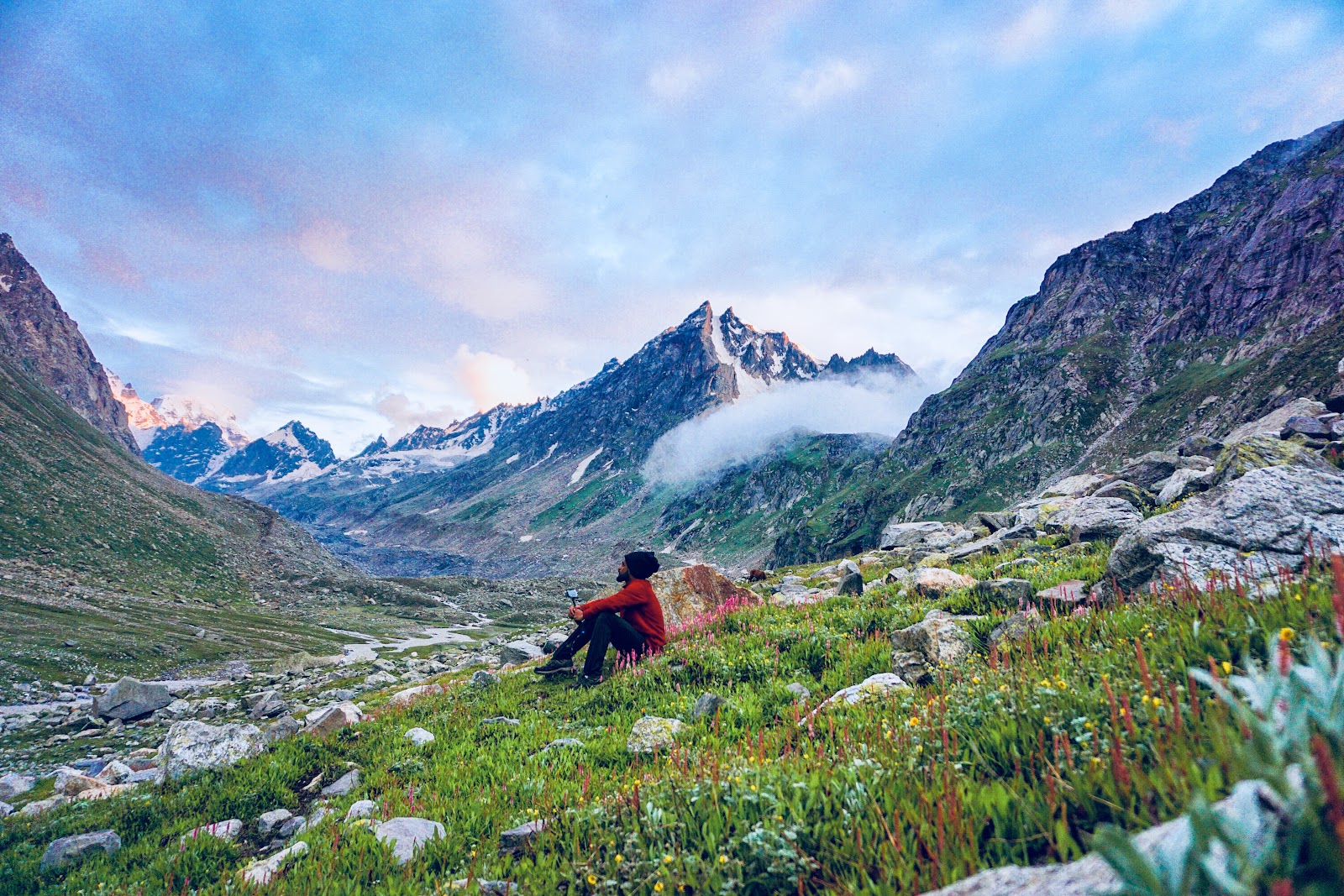 Trekker resting in a wildflower meadow on the Hampta Pass trek